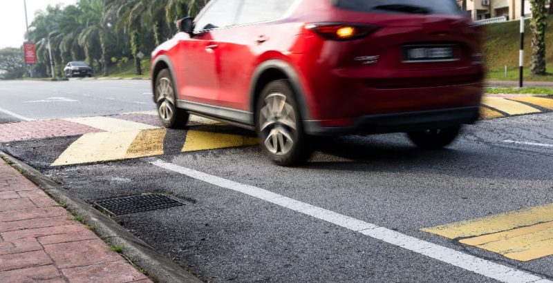 red car driving over speed ramp