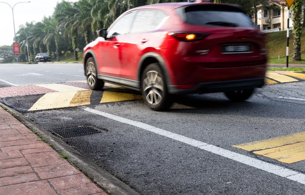 red car driving over speed ramp